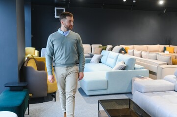 Canvas Print - A handsome young man chooses furniture in a store