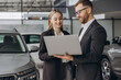 © anatoliycherkas - Portrait of two workers with laptop inside car showroom