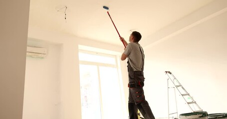 Wall Mural - Male craftsman with roller on long stick paints ceiling white at home. Refurbishment and painting of walls and ceilings