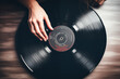 © Prompt2image - top view Woman hand holding vinyl disc on top of table. Music collection. Music passion