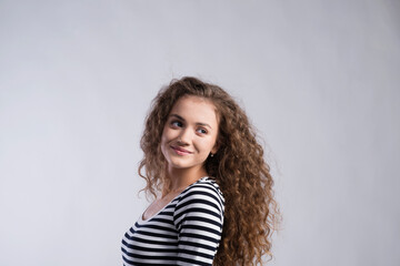 Poster - Portrait of a gorgeous teenage girl with curly hair. Studio shot, white background with copy space