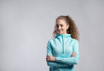 Poster - Portrait of a gorgeous fitness girl with curly hair, wearing workout clothes. Studio shot, white background with copy space