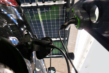 Sticker - Electric car is charged from a charging station that takes energy from solar panels. Close up..