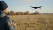 © Lull - Drone flying over autumn field. Man operating a drone with remote control in his hands, flying over an autumn field.