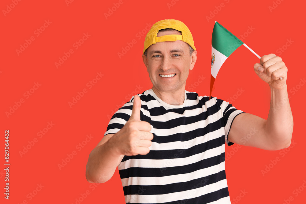 Mature man with Mexican flag showing thumb-up on red background