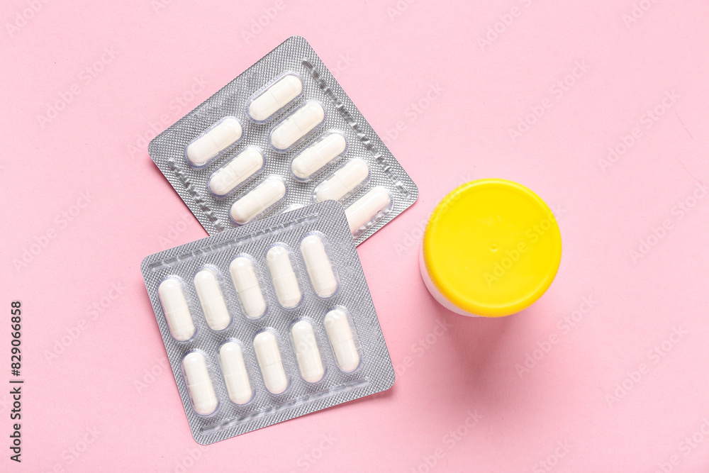 Bottle and blister packs with pills on pink background