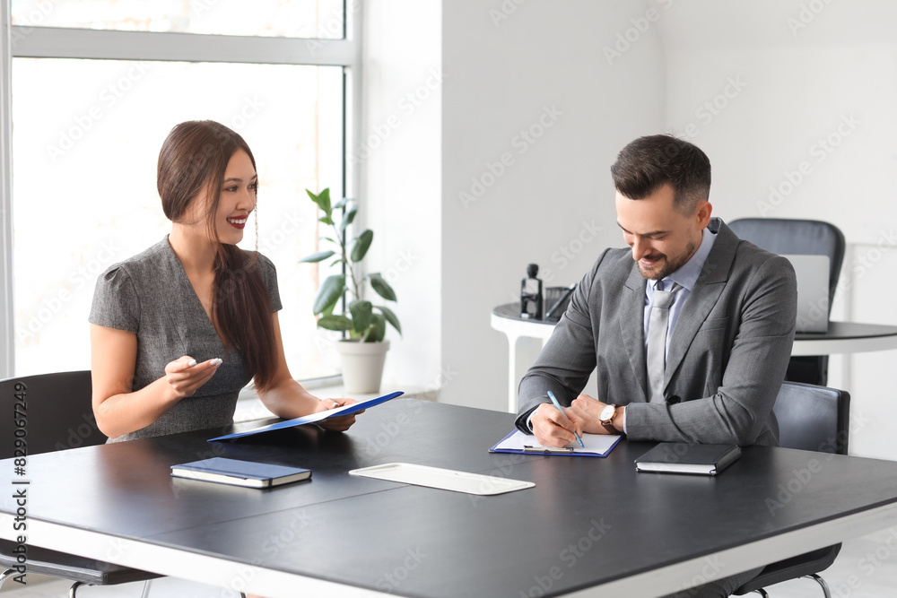 Human resources manager interviewing female applicant at table in office
