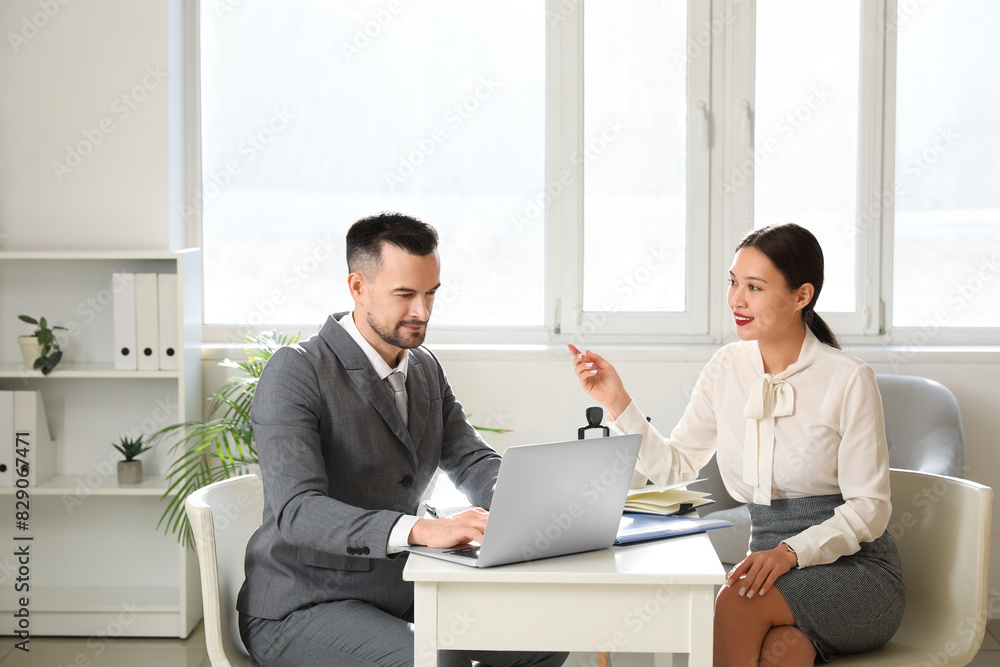 Human resources manager with laptop interviewing female applicant in office
