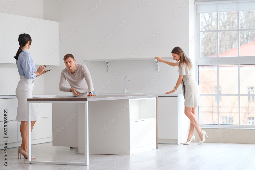 Real estate agent showing young couple kitchen in new house