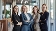 © Tetiana - Mixed age team of female business professionals standing together in a modern office, dressed in formal business attire, smiling confidently. teamwork and success concept
