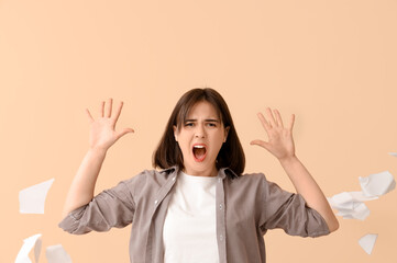 Beautiful young stressed woman tearing paper on beige background. Stress Awareness Month