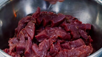 Canvas Print - Chef putting sliced raw beef meat into bowl at commercial kitchen, close up