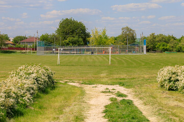 Wall Mural - A large field with a soccer field and a house in the background