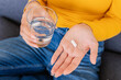 © Xavier Lorenzo - Close up young woman hands holding white pill and glass of water. Vitamins, pills and tablets. Health care and people concept.