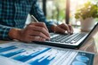 © DWN Media - Business man working with a calculator and laptop on a desk in an office background, a close up of a hand holding a pen using a computer in a modern room for a financial concept