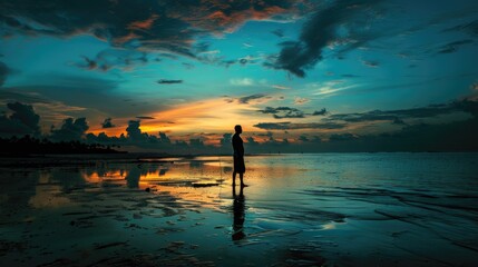 Wall Mural - A man stands on the beach at sunset. The sky is a mix of blue and orange, and the water is calm. The man is alone, and the scene is peaceful and serene
