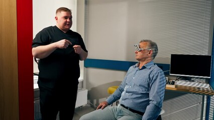 Wall Mural - in an ophthalmology clinic obese doctor consults an elderly patient about lenses