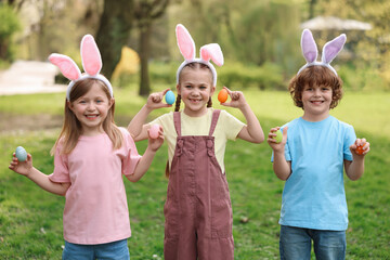 Canvas Print - Easter celebration. Cute little children in bunny ears holding painted eggs outdoors