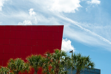 Wall Mural - The exterior wall of a contemporary commercial style building with aluminum metal composite panels. The futuristic corner of a bright red building has engineered diagonal cladding steel frame panels. 