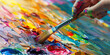 © Lila Patel - A painter dips their brush into a palette of vibrant colors, ready to bring new life to a blank canvas