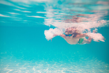 Wall Mural - Child playing in swimming pool. Kids holidays and vacation concept. Summer kid play in swimming pool. Little child boy in pool underwater. Kids swim in pool on summer vacation.