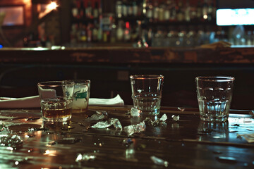 Wall Mural - A bar counter with a glass of water and a few other glasses on it. The counter is wet and has ice cubes on it