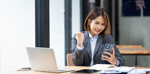 Wall Mural - Beautiful asian woman using smartphone, exciting and celebrating with good news of business successful. Small business startup concept.