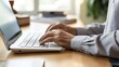© BURINKUL - Close-up of a senior person's hands typing on a laptop keyboard at a desk, focusing on digital skill and technology use.