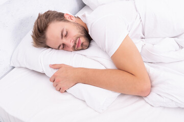 Deep male sleep. Man sleeping at night. Sleepy man lying on bed sleeping at white bedroom. Asleep young man sleeping. Resting peacefully in comfortable bed. Lying with closed eyes. Sick leave