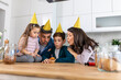 © Graphicroyalty - In the kitchen, a father blows out birthday candles on a cake, surrounded by his happy family. Laughter fills the air as they celebrate together, cherishing the moment of joy and togetherness.