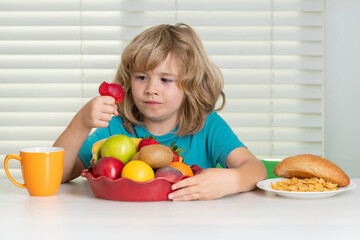 Child with strawberry, summer fruits. Little child boy having healthy breakfast. Children nutrition and development. Eating vegetables by kid make them healthier.