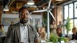 © visoot - An African American man presenting on the use and potential growth of green energy to colleagues at his office, with model wind turbines and solar panels spread out across tables. Generative AI.