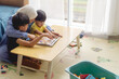 © Dipo - mother with his two son reading a books in a messy living room, concept of parenting and learning
