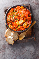 Wall Mural - Vegetable stew of zucchini, peppers, onions, tomatoes and eggplant close-up in a bowl on the table. Vertical top view from above