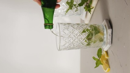 Wall Mural - A refreshing summer drink or alcoholic cocktail with ice, mint and lemon on a sunny day. A fresh healthy cold lemonade drink. Sparkling water with lemon. Vertical video