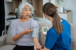 © NINENII - young caregiver assists her elderly woman patient at a nursing home. senior woman is assisted by a nurse at home.