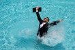 © Volodymyr - Business man in suit with laptop excited jumping in swimming pool. Summer travel tourism and business concept. Crazy office employee using laptop in pool on summer day.