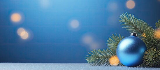 Wall Mural - A Christmas tree branch adorned with a blue ball stands out in the festive copy space image