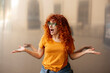 © Westend61 - Cheerful redhead woman with arms outstretched and mouth open standing in front of glass wall