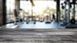 © ffunn - Blurred wooden table view of a modern gym or fitness center in the background. There is a clear focus on the wooden table or counter in the foreground. The wood surface looks rustic