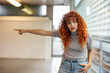 © Westend61 - Angry redhead young woman with curly hair pointing away