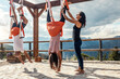 © Westend61 - Fitness instructor assisting woman with aerial yoga near man practicing on silk at class