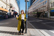 © Westend61 - Fashionable businesswoman with disposable cup leaning on pole in city