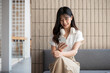 © bongkarn - A beautiful Asian businesswoman sits in a cafe, using her smartphone to check messages.