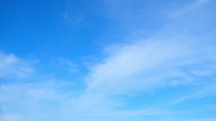 Wall Mural - A clear blue sky with a few wispy clouds scattered across it. The bright blue hue of the sky and the soft white clouds create a calm and serene atmosphere. Blue sky background.
