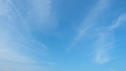 A clear blue sky with a few thin, wispy clouds stretching across it. The gradient from a light blue at the horizon to a deeper blue higher up creates a serene and expansive atmosphere.
