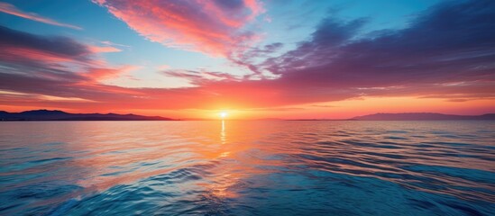 Wall Mural - Vibrant sunset over the sea with a beautiful array of colors reflecting off the rippling water creating a stunning vista with a copy space image