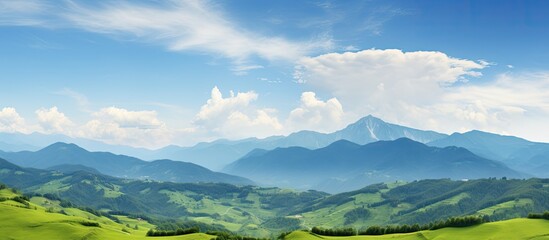 Wall Mural - Lush green mountains set against a blue sky backdrop create a picturesque panorama in this stunning landscape with mountain peaks and valleys offering a breathtaking view with copy space image
