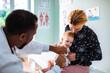 © Marko Geber - Pediatrician vaccinating a baby with mother holding the child in clinic