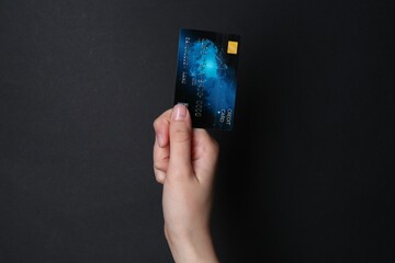 Canvas Print - Woman holding credit card on black background, closeup